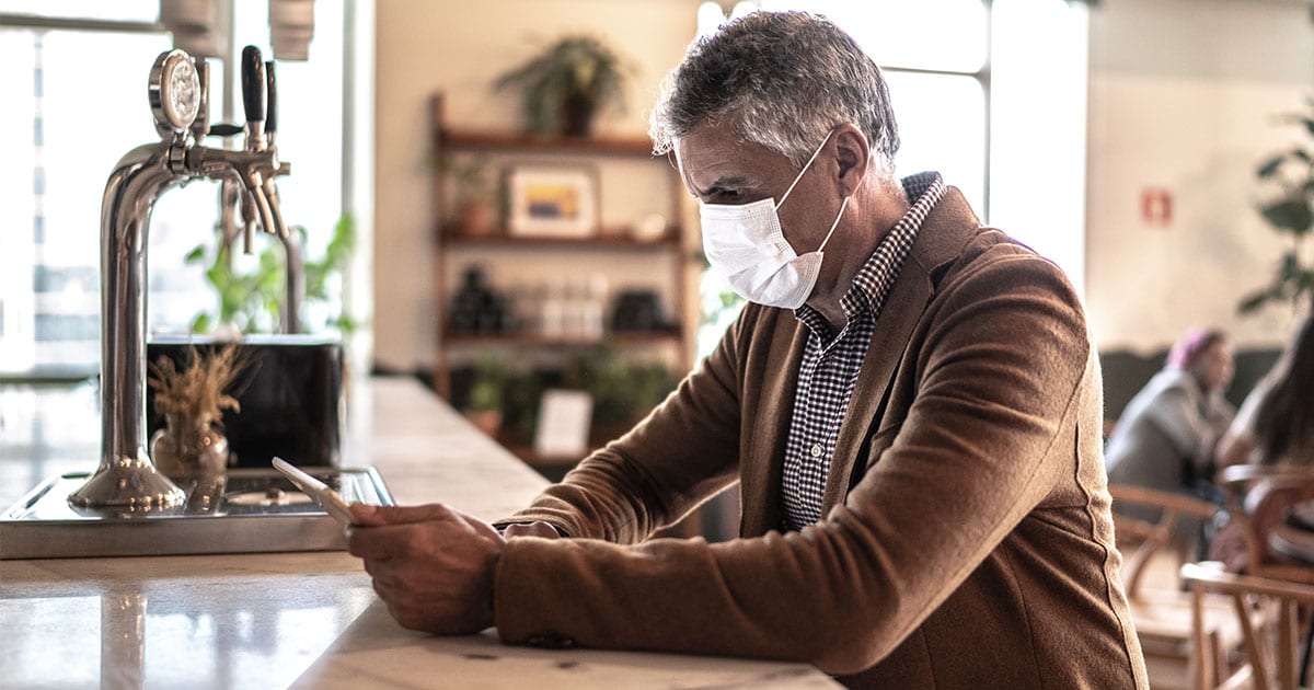 professional man wearing face mask looking at phone